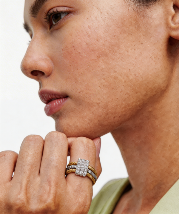 Close-up of a woman's face with a diamond ring on her finger, wearing a light green top.