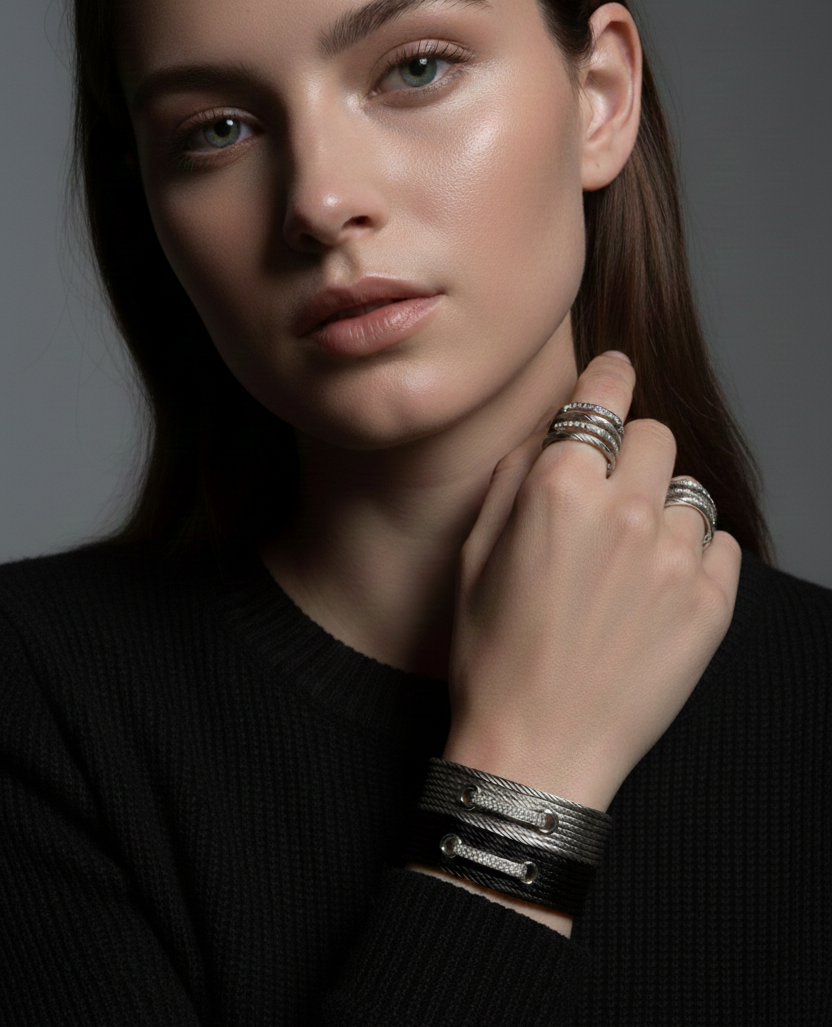 Woman wearing multiple rings and bracelets on a dark background