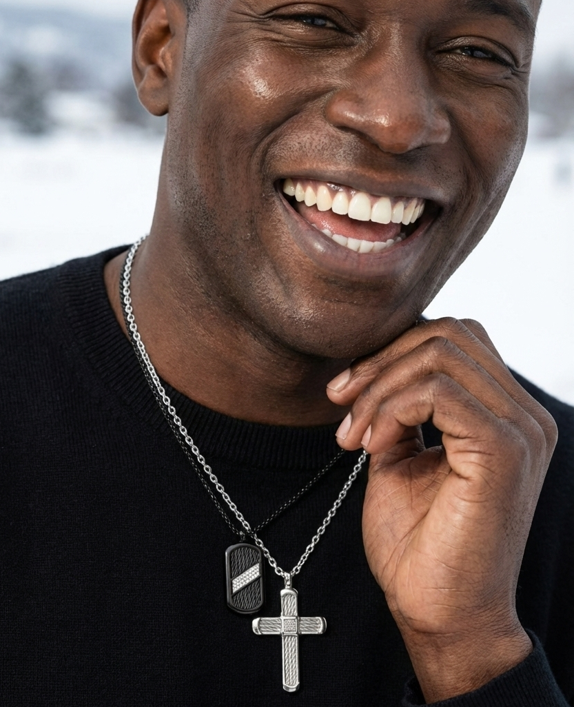 Man wearing a black sweater with a necklace featuring a cross pendant, outdoors.